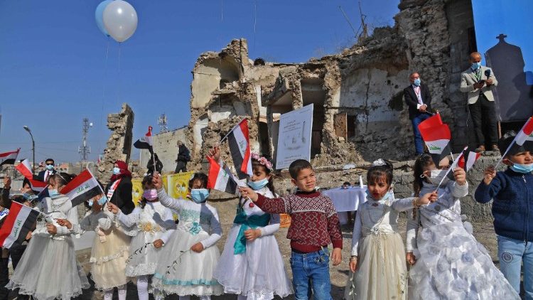 Iraqi children wave flags outside a church during Pope Francis' visit to Mosul in 2021