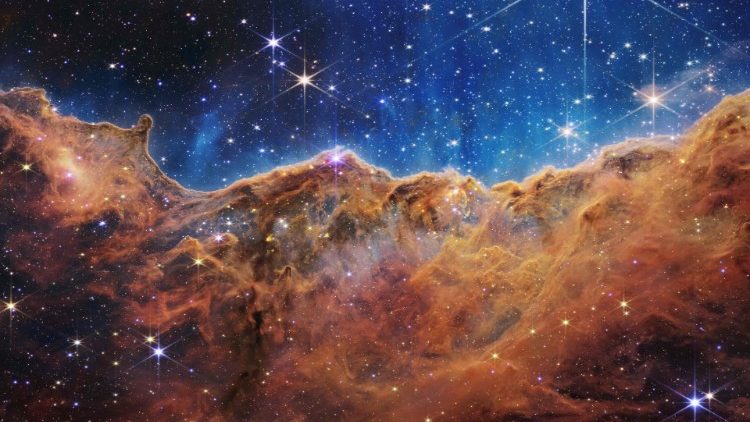 An image from the James Webb Space Telescope shows a landscape of mountains and valleys which is the edge of a nearby, young star-forming region called NGC 3324 in the Carina Nebula