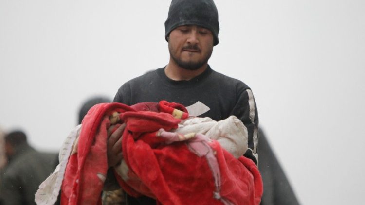 A Syrian man carries the body of an infant killed in the quake