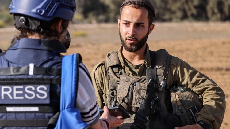 A journalist interviews an Israeli army corporal near the border with the Gaza Strip