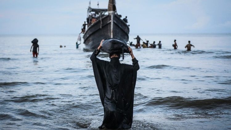 A Newly arrived Rohingya refugee walks to the beach after the local community decided to temporarily allow them to land for water and food, Aceh province, Indonesia
