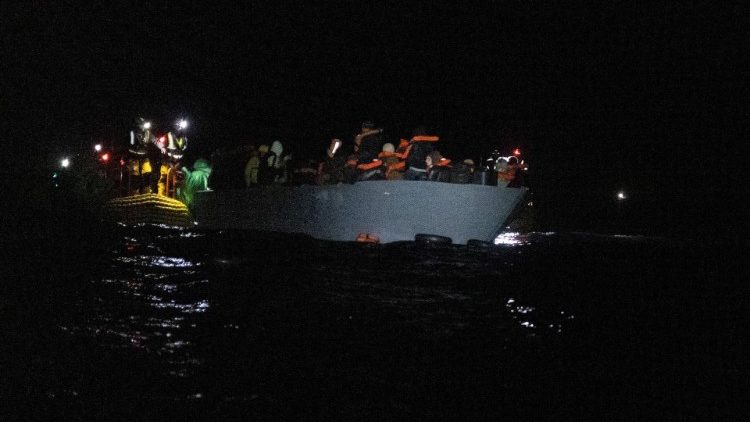 Rescuers assist migrants drifting aboard a dinghy off the coast of Libya