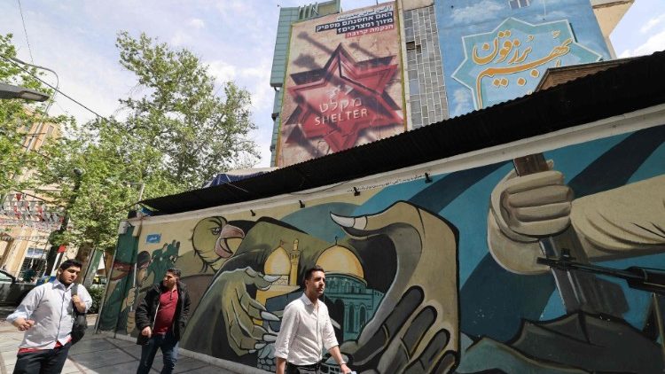 Iranians walk next to an anti-Israel poster in Tehran on 13 April.