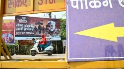 Eine Frau auf einem Roller vor einem Wahlplakat mit Indiens hindu-nationalistischem Premierminister Narendra Modi