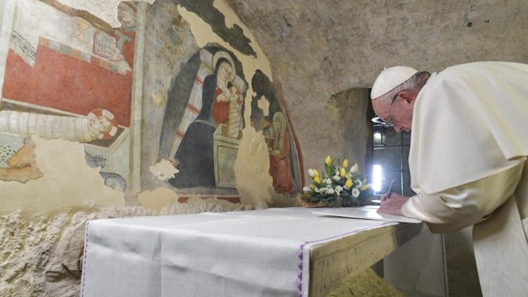 Momento em que Papa Francisco assina a Carta Apostólica Admirabile Signum diante de afrescos do Presépio em Greccio