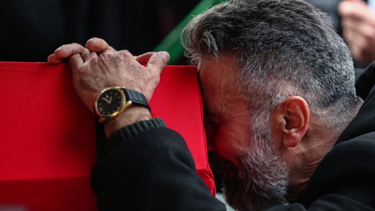 A man weeps while holding on to the coffin of his daughter and wife killed in the bombing 