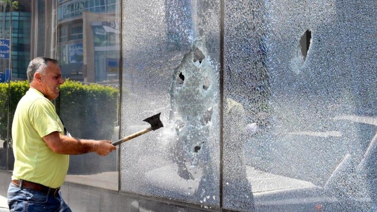 A bank customer smashes the glass front of a bank in Beirut