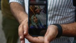 Kassem Abo Zeed, 34, da Síria, segura uma foto em seu celular de sua esposa desaparecida Israa que estava no navio com refugiados e migrantes que afundou em Pylos. EPA/YANNIS KOLESIDIS