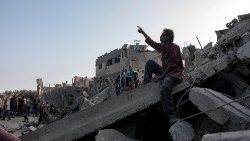 A Palestinian man sits on the rubble of a building at the Maghazi refugee camp in Gaza