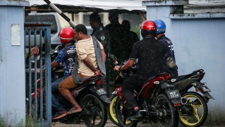 Malaysian authorities escort a handcuffed detainee towards a detention centre, Malaysia