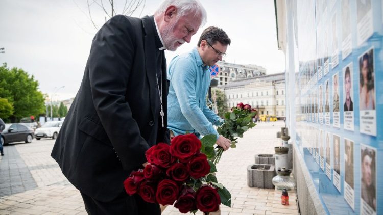 Mgr Gallagher dépose un bouquet au pied du mur du souvenir, érigé en mémoire des soldats ukrainiens tués, à Kiev le 20 mai 2022, aux côtés du ministre ukrainien des Affaires étrangères ,Dmytro Kuleba. 
