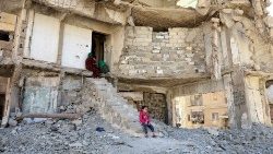 Menschen sitzen in den Trümmern eines zerstörten Hauses in der Stadt Raqqa