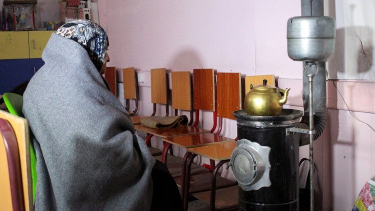 Kobieta przy piecyku w szkole przekształconej na tymczasowy schron dla ludności