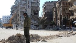 In Aleppo, a man stands in front of buildings destroyed by the quake