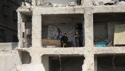 Syryjska rodzina siedząca w częściowo zniszczonym w trzęsieniu ziemi domu w Aleppo, 13 lutego 2023
