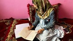 Sofia, an Afghan student, takes notes during an online class, at her house in Kabul
