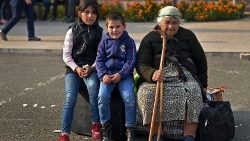 Uma mulher idosa e crianças sentam-se em sacos com pertences enquanto os residentes se reúnem no centro de Stepanakert para deixar Nagorno-Karabakh, uma região habitada pela etnia armênia, em 25 de setembro de 2023. REUTERS/David Ghahramanyan