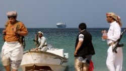 Uomini armati in piedi sulla spiaggia mentre la nave commerciale Galaxy Leader, sequestrata dagli Houthi dello Yemen il mese scorso, è ancorata al largo della costa di al-Salif