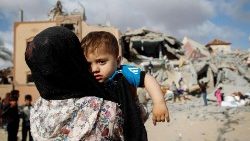 Una mamma col suo bambino di fronte alla distruzione di Rafah