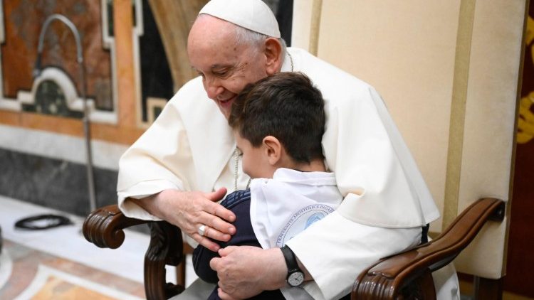 Der Papst umarmt ein Kind