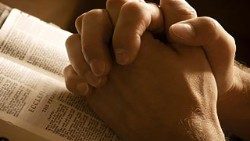 Zum Gebet gefaltete Hände auf einer Bibel