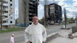 El padre Jaroslaw Krawiec, vicario de los dominicos en Ucrania, delante de los edificios bombardeados