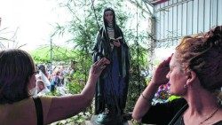 Des fidèles en prière devant une statue de Mama Antula. 