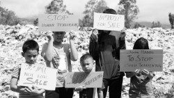 Niños con mensajes escritos para pedir que "pare la trata de personas".