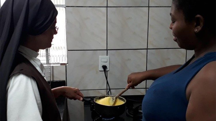 Una suora aiuta una donna a preparare il cibo per i bambini