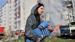 Žena v Ukrajini beži s svojim otrokom pred bombardiranjem.