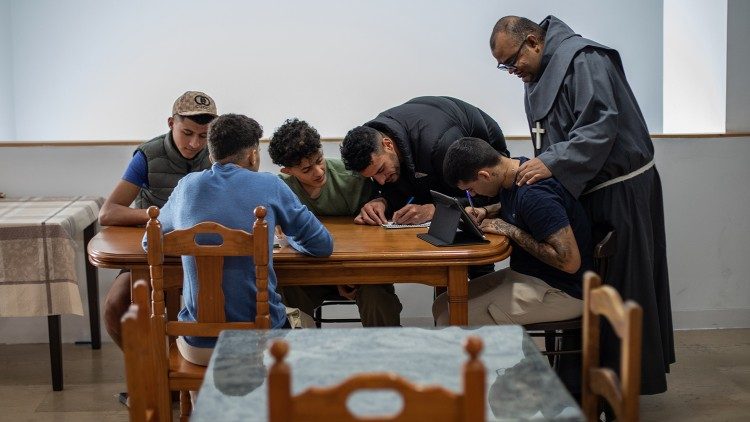 Abdeslam Ibn Yauch (wearing the black coat) and Friar Giovanni Alseco help four young Moroccans who have just arrived in Algeciras fill out residence permit forms. (Giovanni Culmone/GSF)