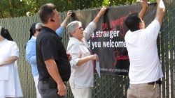 Sister Elaine (center) and friends hang a banner along a busy street to show their support of immigrants, portraying an adaptation of Jesus’ saying, "I was an immigrant and you welcomed me."