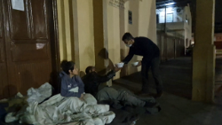 Voluntaria del grupo CES Mãos em Ação reparte raciones de comida a personas sin hogar, que han encontrado refugio frente a una iglesia, en Canoas.