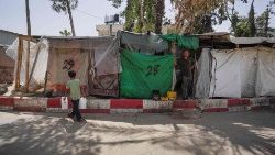 A displaced Palestinian boy carries jerricans of water as he walks in front of tents set up inside the European hospital compound in Khan Yunis