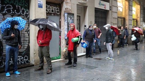 Persone davanti alla chiesa di S. Anna a Barcellona in attesa di pacchetti alimentari (Reuters)