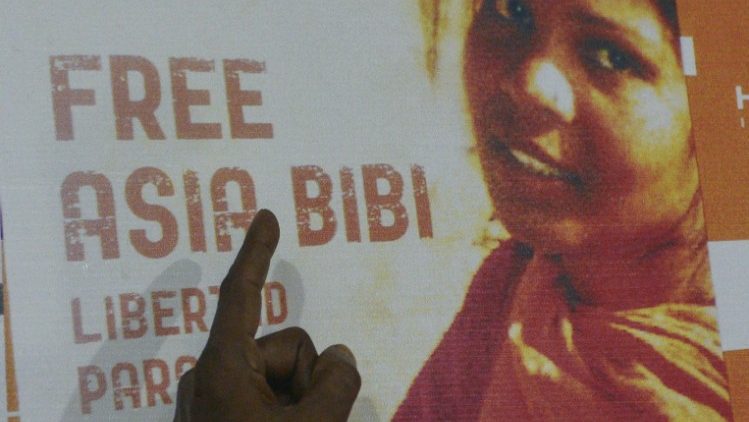 Fotografie z roku 2016: Manžel Asii ukazuje na plakát volající po jejím osvobození
