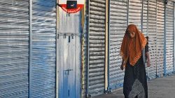 A woman walks next to closed shops in Sri Lanka's capital Colombo