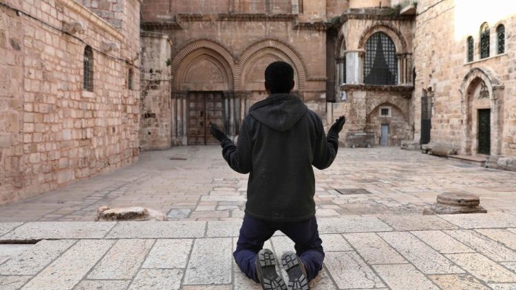 Keresztény hívő imádkozik a lezárt Jeruzsálemi Szent Sír bazilika előtt