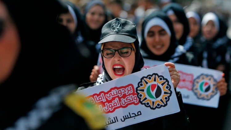 Palestinian protesters march with signs in protest against Israel's annexation plans