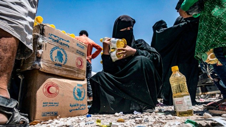 A woman holding bottles of sunflower oil distributed as part of food aid to a displaced persons camp in northeastern Syria (file photo)