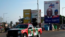 A campaign vehicle of the opposition NDC drives past a billboard of Nana Akufo-Addo, the President and NPP candidate
