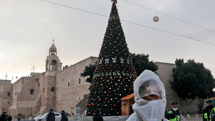 Blick auf die Geburtskirche und den Weihnachtsbaum am Krippenplatz in Bethlehem - ein Arbeiter desinfiziert die Umgebung in Vorbereitung auf die Mitternachtsmesse