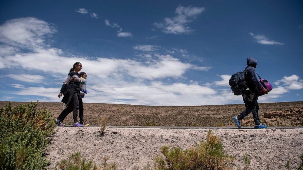 A family of Venezuelan migrants walk along a road in Chile