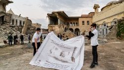 Jóvenes despliegan un cartel de bienvenida al Papa Francisco en las ruinas de la iglesia católica siria de la Inmaculada Concepción en Iraq.