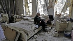 File photo of a man sitting in his bombed-out house in Aleppo in 2017