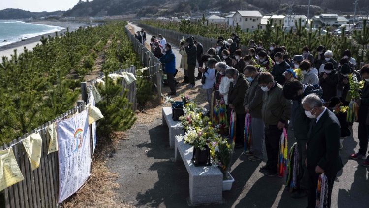 Des habitants de la province de Fukushima observent une minute de silence face à la mer, en mémoire de l'anniversaire de la catastrophe nucléaire, le 11 mqrs 2021. (Charly Triballeau/AFP)