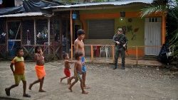 Colômbia. Índios caminham com seus filhos sob a vigilância de soldados na região de Embera, departamento de Chocó