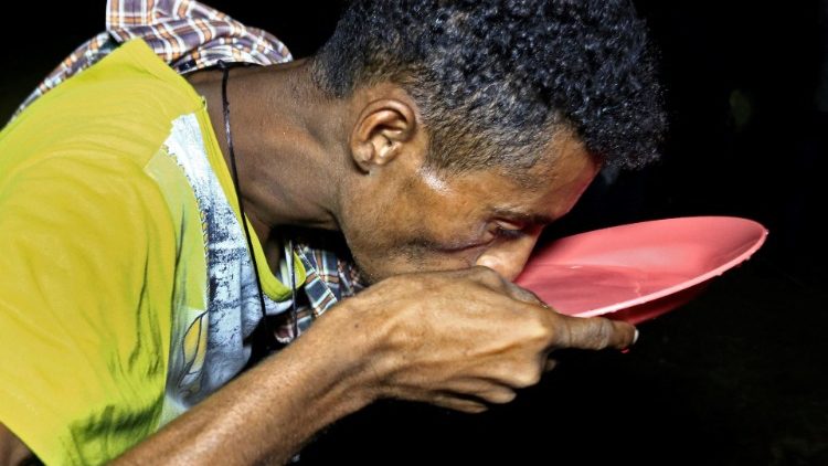 A man drinks from a plate after having fled his hometown in Eithiopia's Tigray region - Um Qaquba camp, Sudan