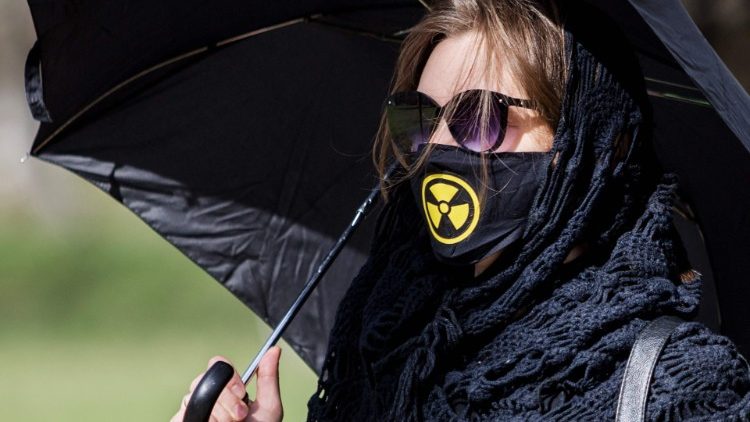 Vestida de negro y una máscara contra la radioactividad, una manifestante conmemora a las víctimas de Chernobyl, el 26 de abril de 2021, a 35 años de la tragedia.