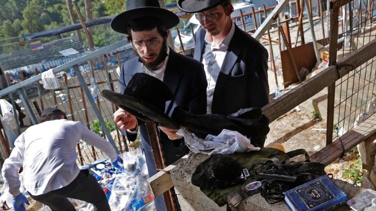 A man checks the personal belongings of Jewish pilgrims piled up at the scene of a stampede during a religious gathering in Meron
